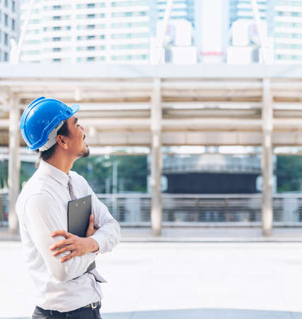 Engineer man hands holding hardhat white work helmet hard hat for Civil Construction Engineering. Construction engineer man in safety suit hold white work helmet hard hat on hands at Construction Siteの写真素材