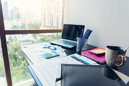 Office laptop business financial document chart and graph on wooden table with coffee cup. Flat lay notebook computer laptop on office desk. No people business graph chart mockup on business workspaceの写真素材