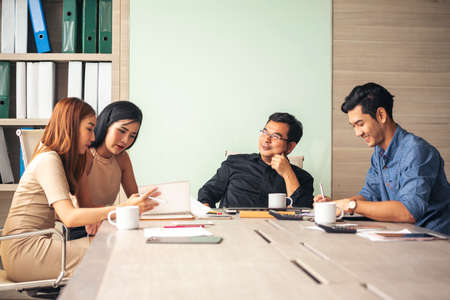 Happiness diversity business team meeting corporate office desk in company meeting room. Asian team group partner brainstorming discussion multiethnic people sitting share ideas teamwork in boardroomの写真素材