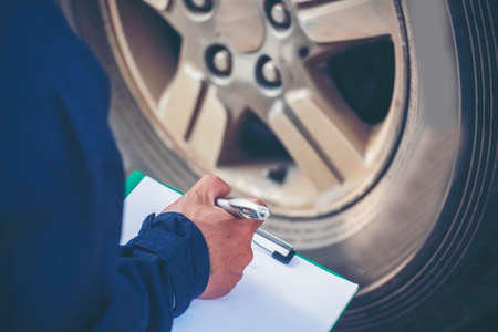 Mechanic man hands checking car tires outdoor on site service auto garage for automotive mobile center services. Technician workshop repair checking tyres car motor vehicles service mechanical handsの写真素材