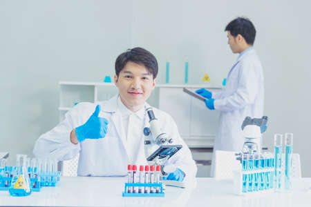 Two asian scientist team reserch chemistry science tube experiment biotech antibody sample in laboratory Cultivate Vaccine against covid-19 virus. Scientist consult, analyze in Chemistry Laboratoryの写真素材