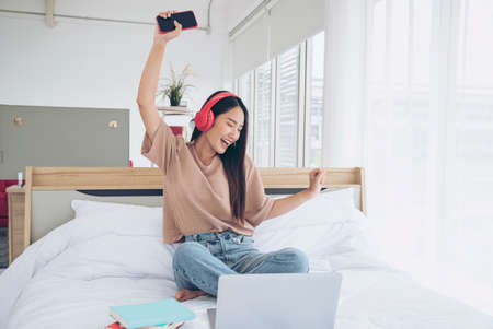 Relax woman holding book read on bed using headphone listen music. Young woman relaxation reading open book leisure mind. Happiness beautiful woman personの写真素材