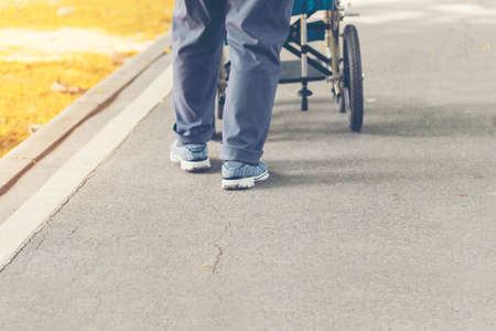 Senior woman try to exercise by walk around the park by using wheelchair. Health care conceptの写真素材