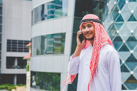 Islamic man using smartphones app organize schedule agenda  focus on hands holding smartphone muslim modern uae city. Arab men wear hijab and muslim formal dress sending text sms online lifestyleの写真素材