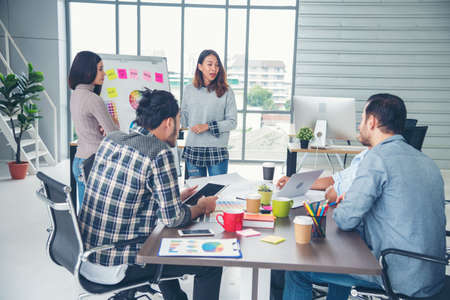 Creative design office center working teamwork. Happy business people partner plan strategy organization research people together at diversity office using laptop, smartphone company conference roomの写真素材