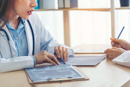 Two asian women doctors discuss meeting doctor's office medical clinic looking x-ray film consulting...