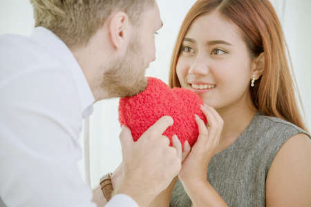 Couple lover in love smile and looking eyes each other with happiness romantic relationship. Couple lover holding red heart shape symbol of love. Close up face shot love at first sight flirting dateの写真素材
