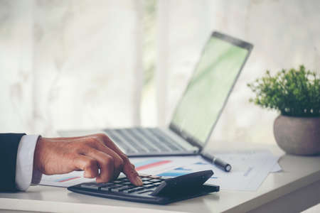 Close up Man hands calculating number, data, graph, chart audit planning accountancy on business report. Business man hands using calculator counting tax financial bill.  Tax audit Finacial concept.の写真素材