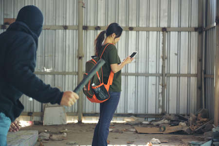 Thief armed man rob woman by baton on street stalker behind young woman back. Woman on phone...