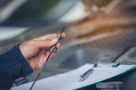 Car Mechanic man hand checking dipstick engine oil car mechanical on site service. Close up hand man check engine oil level Locate dipstick, wipe clean, check dipstick level before fill up engine oilの写真素材