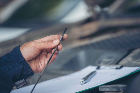 Car Mechanic man hand checking dipstick engine oil car mechanical on site service. Close up hand man check engine oil level Locate dipstick, wipe clean, check dipstick level before fill up engine oilの写真素材