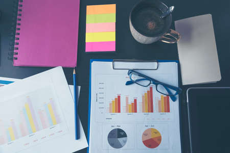 Office laptop business financial document chart and graph on wooden table with coffee cup. Flat lay notebook computer laptop on office desk. No people business graph chart mockup on business workspaceの写真素材