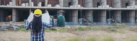 Banner Woman construction engineer hold blueprint wear plaid shirt safety white hard hat at construction site industry. Panorama Architecture Female civil engineer look at blueprint with copy spaceの写真素材
