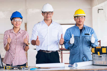 Construction engineer teamwork Safety Suit Trust Team Holding White Yellow Safety hard hat Security Equipment on Construction Site. Hardhat Protect Head for Civil Construction Engineer Conceptの写真素材