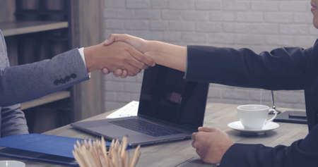 Team Business Partners shaking hands together to Greeting Start up new project. Shakehand Teamwork Partnership at office desk. Businessman partners handshake together.  Business conceptの写真素材