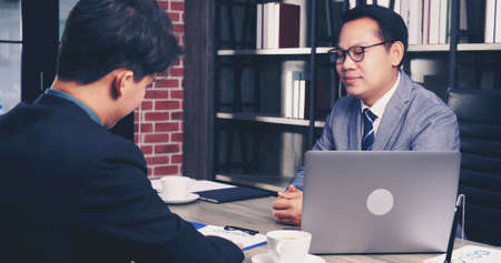 Two Businessman signing contract document start business agreement dealing teamwork. Close up hand young man colleagues  meeting mergers and acquisitions business. Partners Signed document at office.の写真素材