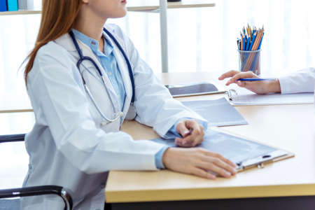 Two asian women doctors discuss meeting doctor's office medical clinic looking x-ray film consulting...