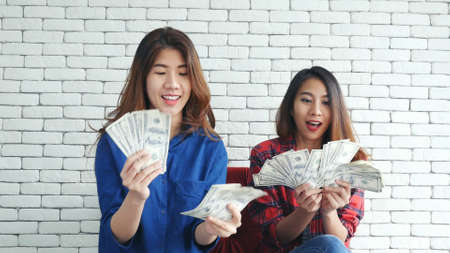 Happy young asian woman holding dollar money and throw in the air celebrate happiness dance wealth lottery money rain drop. Winner Success business woman throw cash flow Happy money smiling faceの写真素材