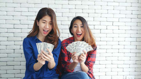 Happy young asian woman holding dollar money and throw in the air celebrate happiness dance wealth lottery money rain drop. Winner Success business woman throw cash flow Happy money smiling faceの写真素材