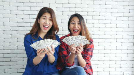 Happy young asian woman holding dollar money and throw in the air celebrate happiness dance wealth lottery money rain drop. Winner Success business woman throw cash flow Happy money smiling faceの写真素材