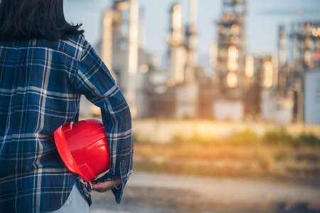 Refinery plant woman worker oil petrochemical industry hand holding red worker hard hat. Woman...