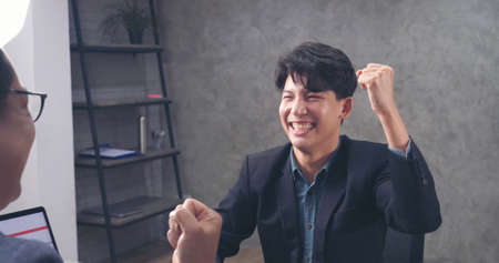 Two businessmen talking together at office desk, business meeting room with happiness and make high five for good news. High five Two partner executive young man meeting team solidarity power conceptの写真素材