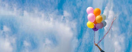 Banner Cheerful cute girl holding balloons running green meadow white cloud and blue sky with happiness. Panorama Hands holding vibrant air balloons happy times summer sunlight outdoor copy spaceの写真素材