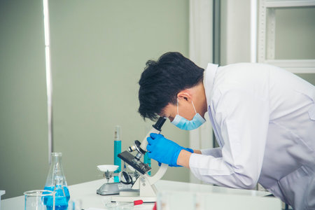 Scientist man look into Microscope research in science laboratory. Asian scientist looking equipment laboratory chemistry labs.  virus biochemistry research experiment vaccine conceptの写真素材
