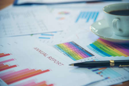 Office laptop business financial document chart and graph on wooden table with coffee cup. Flat lay notebook computer laptop on office desk. No people business graph chart mockup on business workspaceの写真素材