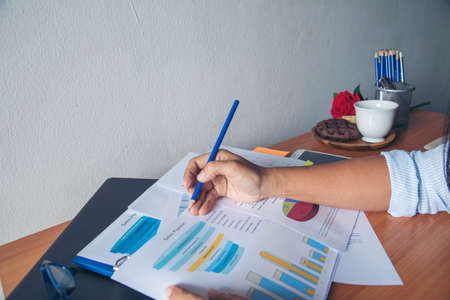 Business woman using smartphone, laptop on office desk. Female freelance reading financial graph charts Planning analyzing marketing data. Hands of young woman working in office firm business info.の写真素材