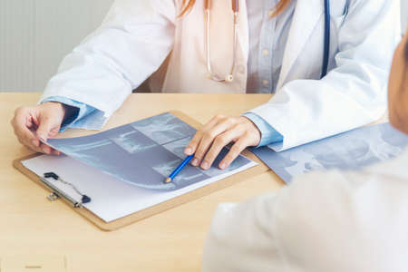 Close up hands of two women doctor medical lab discussing together healthcare teamwork. Two asian women hand doctors meeting write prescription medical clinic. Doctor discuss using laptop write noteの写真素材