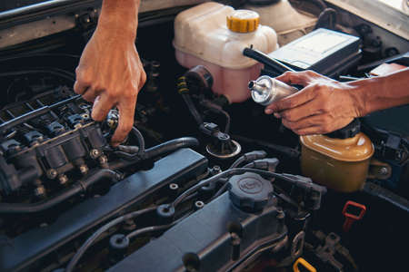 Close up Car Mechanic man hands repairing car auto repair shop. Man hands fixing machinery vehicle mechanical service. open vehicle hood checking up auto mobile. Vehicle Car maintenance engineer.の写真素材