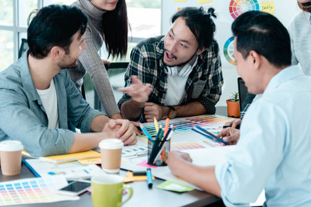 Creative design office center working teamwork. Happy business people partner plan strategy organization research people together at diversity office using laptop, smartphone company conference roomの写真素材