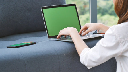 Empty Screen laptop Blogger Woman hands typing computer keyboard. Close up women hands using laptop sitting at sofa in living room. Freelance girl work from home office via internet call conferenceの写真素材