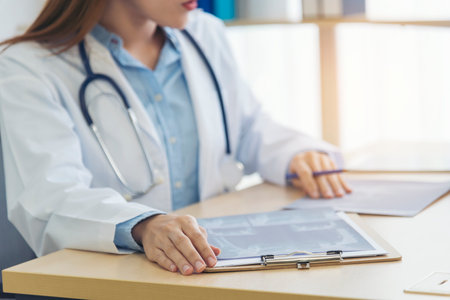 Close up hands of women doctor write prescription medical lab hospital. Crop asian women hand doctors working in medical clinic looking CAT scan xray film. Doctor with stethoscope writing on notepadの写真素材