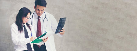Banner Two asian doctors discuss meeting office medical clinic. Young asian female doctor looking...