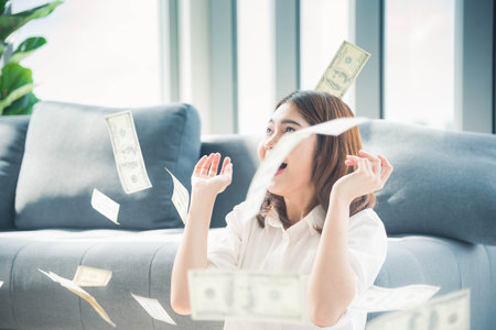 Happy young asian woman holding dollar money and throw in the air celebrate happiness dance wealth lottery money rain drop. Winner Success business woman throw cash flow Happy money smiling faceの写真素材