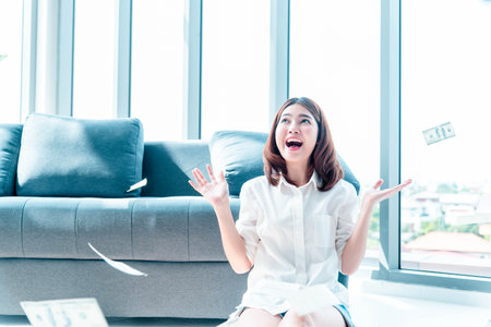 Happy young asian woman holding dollar money and throw in the air celebrate happiness dance wealth lottery money rain drop. Winner Success business woman throw cash flow Happy money smiling faceの写真素材