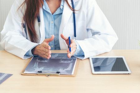 Close up hands of women doctor write prescription medical lab hospital. Crop asian women hand doctors working in medical clinic looking CAT scan xray film. Doctor with stethoscope writing on notepadの写真素材