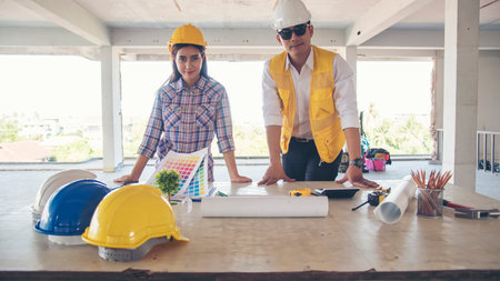 Asian engineer man brainstorming construction building contractor civil worker parners team meeting at constrcution site. Blueprint engineer hardhat worker helmet on table. Engineer teamwork consultの写真素材