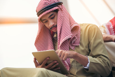 Islamic man using smartphones app organize schedule agenda  focus on hands holding smartphone muslim modern uae city. Arab men wear hijab and muslim formal dress sending text sms online lifestyleの写真素材