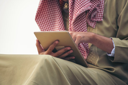 Islamic man using smartphones app organize schedule agenda  focus on hands holding smartphone muslim modern uae city. Arab men wear hijab and muslim formal dress sending text sms online lifestyleの写真素材