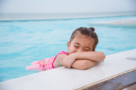 Toddler girl have fun swimming pool summer time with swimwear in blue water at hotel swimming pool outdoor. Kid swim playful water splash with happiness on summer vacation. Happy girl swim conceptの写真素材
