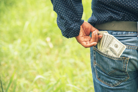 Hand holding money dollar bank note in wallet give financial payment. Man hands showing spread 100 dollar exchange cash payout. Saving Businessman counting money banknote bribe corruption concept.の写真素材