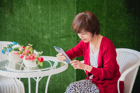 Asian woman using digital tablet shopping online, call, texting message internet technology lifestyle with smiling face. Asian woman touch smart tablet focus on hands using mobile app home office.の写真素材