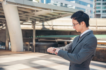 Asian businessman wear suit, eye glasses standing street in modern city. Portrait Young handsome asian man look at bright future smart, confident. Entrepreneur executive man cityscape outside officeの写真素材