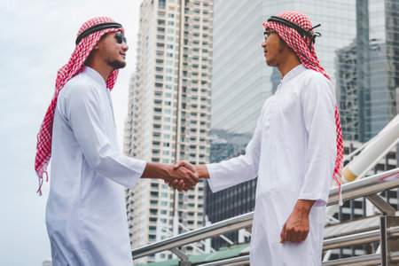 Arab Businessman Muslim dress shaking hands together. Muslim Men Teamwork business partner handshake with business Partnership. Close up hand UAE diversity multiracial people trust honesty commitmentの写真素材