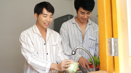 Asian two Man hands wash cleaning fresh vegetable in kitchen. Happy Asian gay couple homosexual cooking together in kitchen wash vegetable organic salad healthy home cook. LGBTQIA lifestyle conceptの写真素材