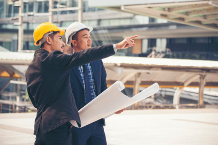 Civil engineer teams meeting working together wear worker helmets hardhat on construction site in modern city. Foreman industry project manager engineer teamwork. Asian industry professional teamの写真素材