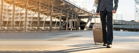 Banner Businessman walking luggage in business trip. Focus on man legs travel arrival terminal. Business travel trip holding suitcase at airport. Panorama business man traveller with copy spaceの写真素材